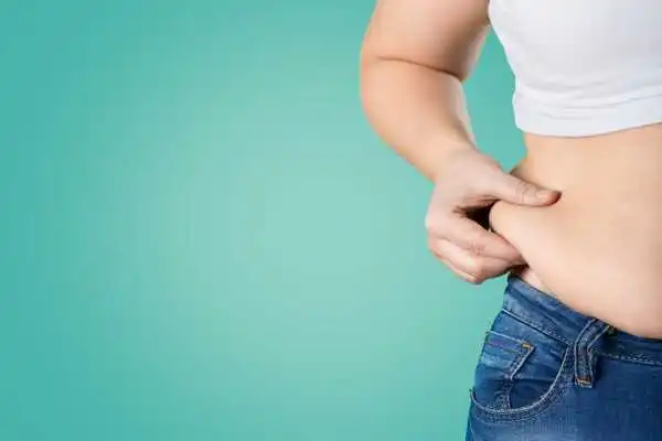 Image of woman pinching her love handles to show weight gain Theale
